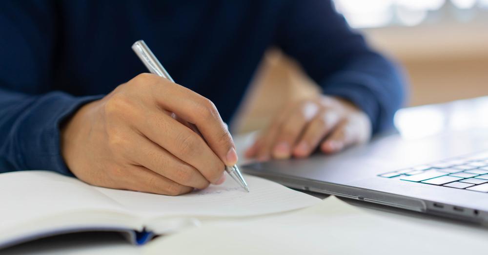 businessman-hand-writing-content-somethings-notebook-with-using-laptop